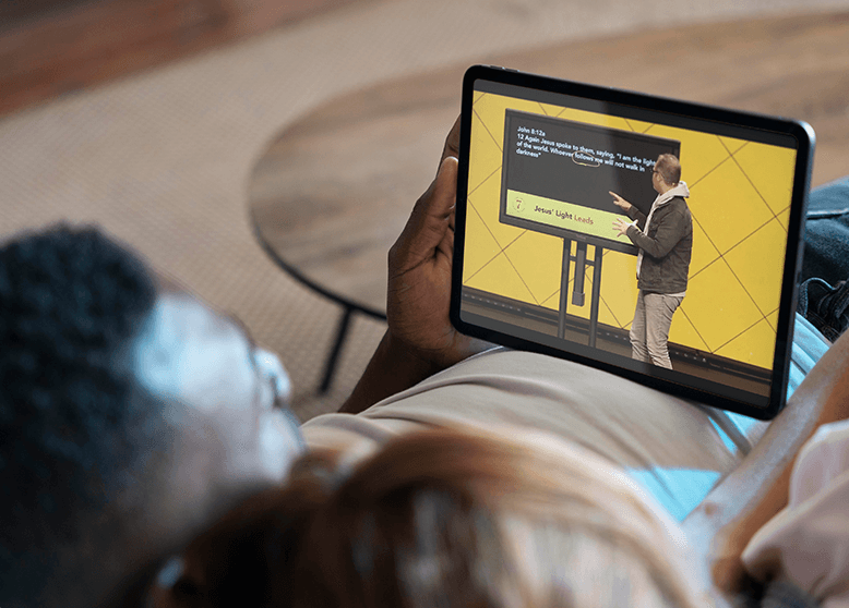 Person watching a sermon on a tablet from their couch